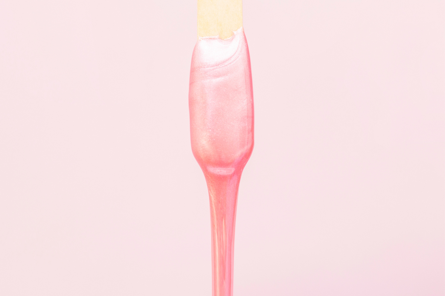 liquid wax for pink depilation drains from the stick. The concept of depilation, waxing, smooth skin without hair.