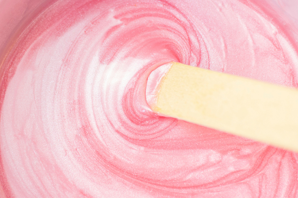 background texture liquid wax for depilation of pink color with mother of pearl with a stick. The concept of depilation, waxing, smooth skin without hair.